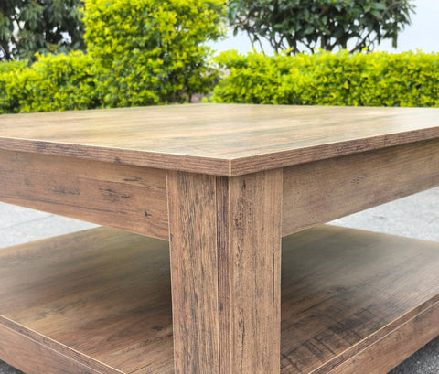 Rustic knotty oak coffee table in a farmhouse-style living room
Side view showing woodgrain texture and lower shelf
Top-down view of the square table surface
Decorated coffee table with books and storage baskets
Compact rustic wood table styled with cozy furniture