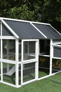 Wooden chicken coop featuring attached nesting box and easy-access doors