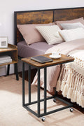 Rustic side table with laptop on top near sofa
Rolling wood TV tray with black metal legs
End table with wheels next to couch
Industrial-style side table for laptop and coffee