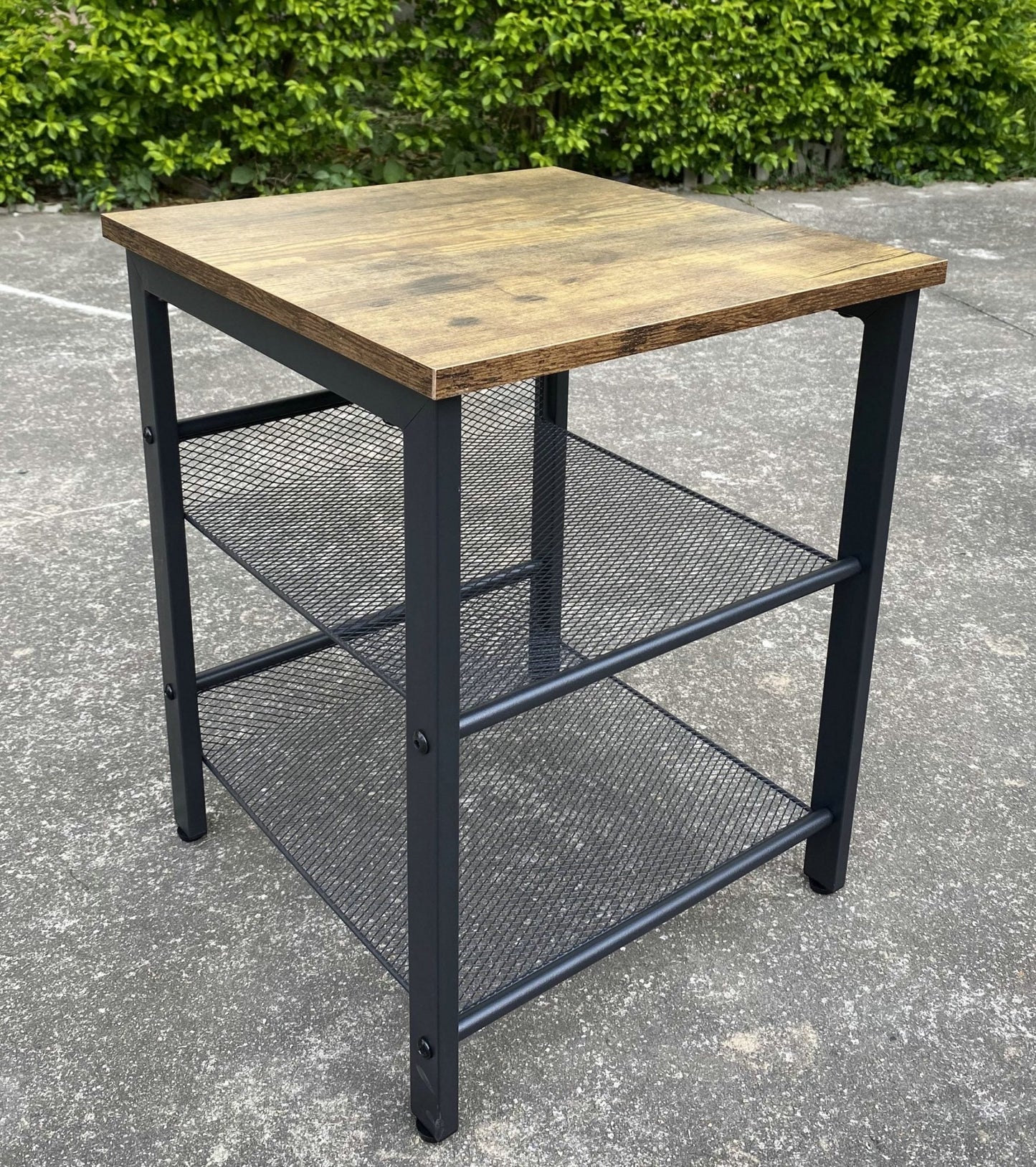 Rustic end tables in a cozy living room setting with sofa and lamp

Side View: Square wood top table with black mesh shelf

Angled View: Rustic wood and black metal table with adjustable shelf

Front View: Front profile of industrial end table with wood top and mesh shelf

Top View: Close-up of wood grain tabletop with rounded edges