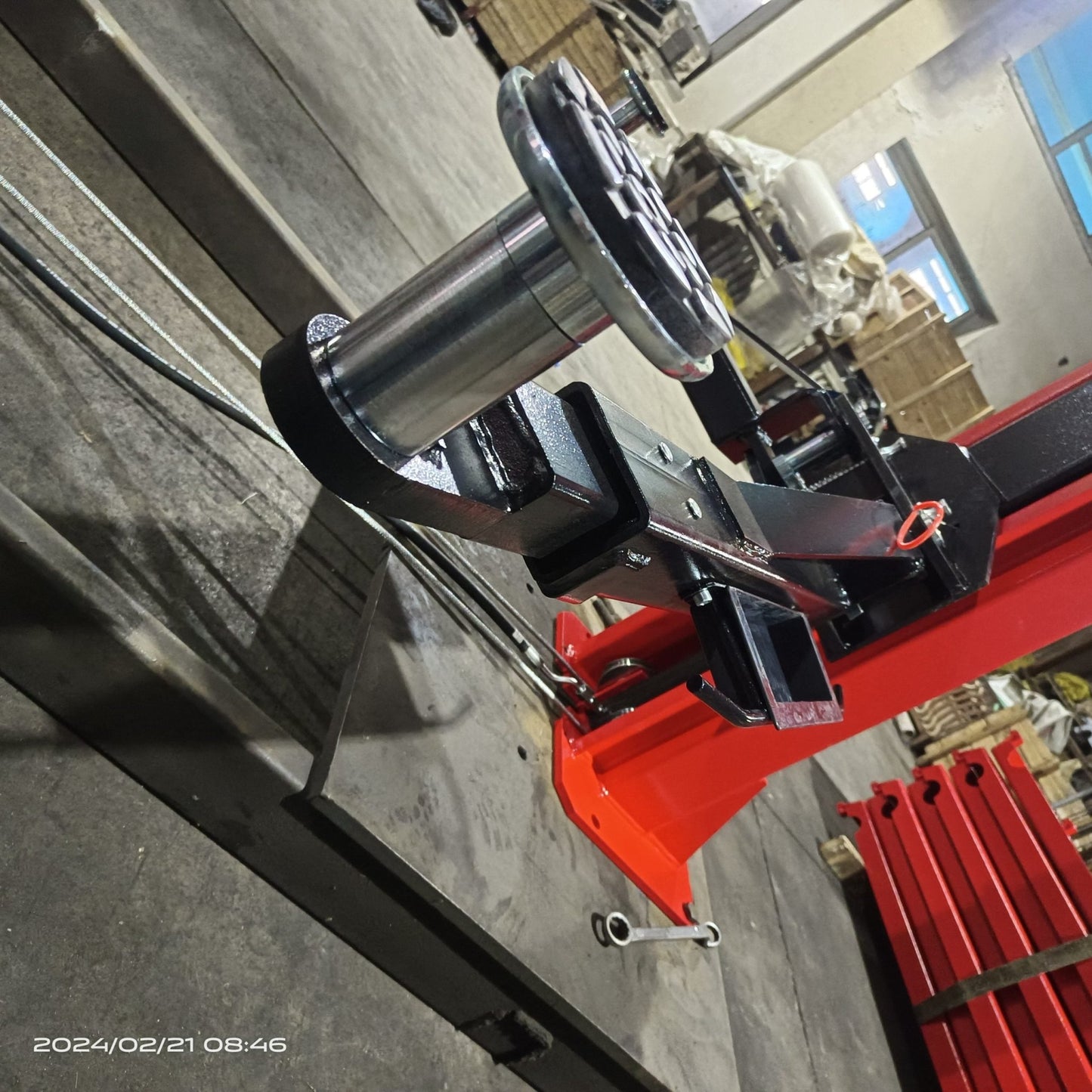 2-post vehicle lift in red installed in garage

Close-up of lifting arms and safety lock mechanism

Base of hoist with truck tires for scale

Top bar and hydraulic system – JH5000F model