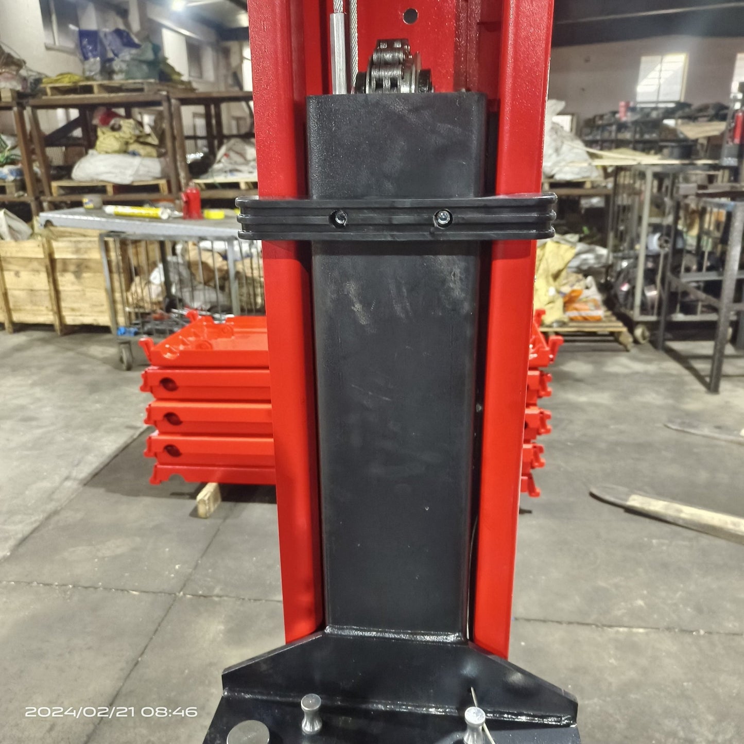 2-post vehicle lift in red installed in garage

Close-up of lifting arms and safety lock mechanism

Base of hoist with truck tires for scale

Top bar and hydraulic system – JH5000F model