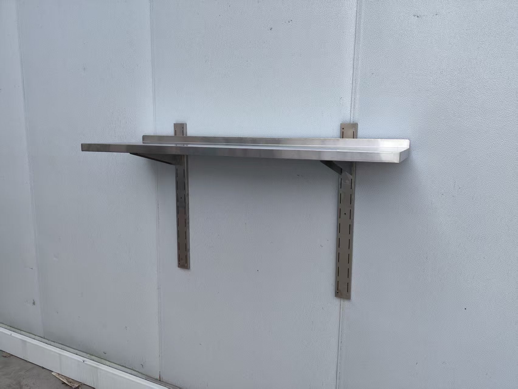 Stainless steel wall-mounted shelf front view

Close-up of shelf bracket and mounting

Side view of stainless steel shelf over prep station

Commercial wall shelf above kitchen counter

Single-tier wall shelf with polished finish