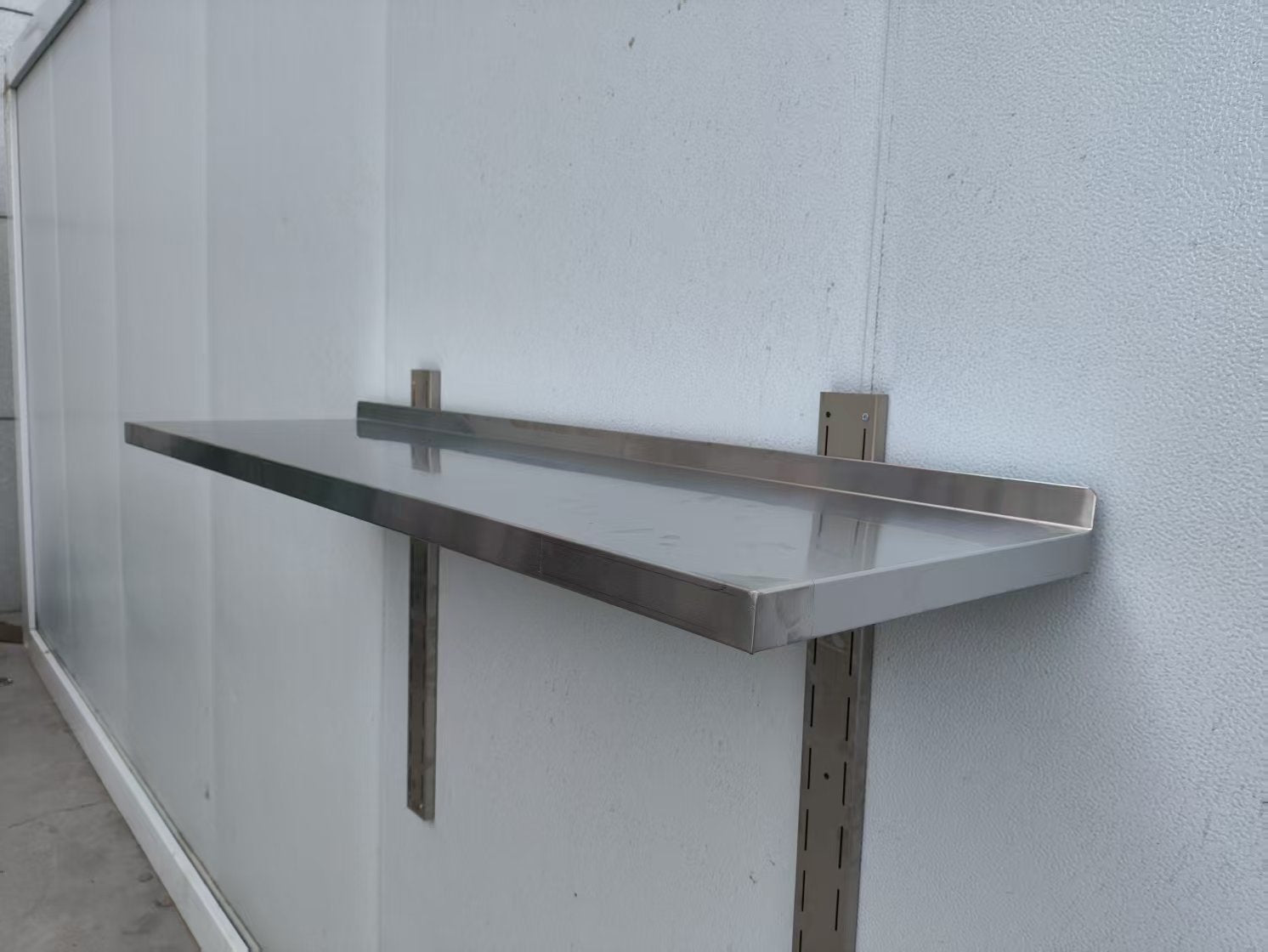 Stainless steel wall-mounted shelf front view

Close-up of shelf bracket and mounting

Side view of stainless steel shelf over prep station

Commercial wall shelf above kitchen counter

Single-tier wall shelf with polished finish