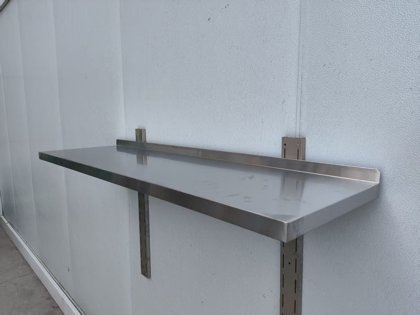 Stainless steel wall-mounted shelf front view

Close-up of shelf bracket and mounting

Side view of stainless steel shelf over prep station

Commercial wall shelf above kitchen counter

Single-tier wall shelf with polished finish