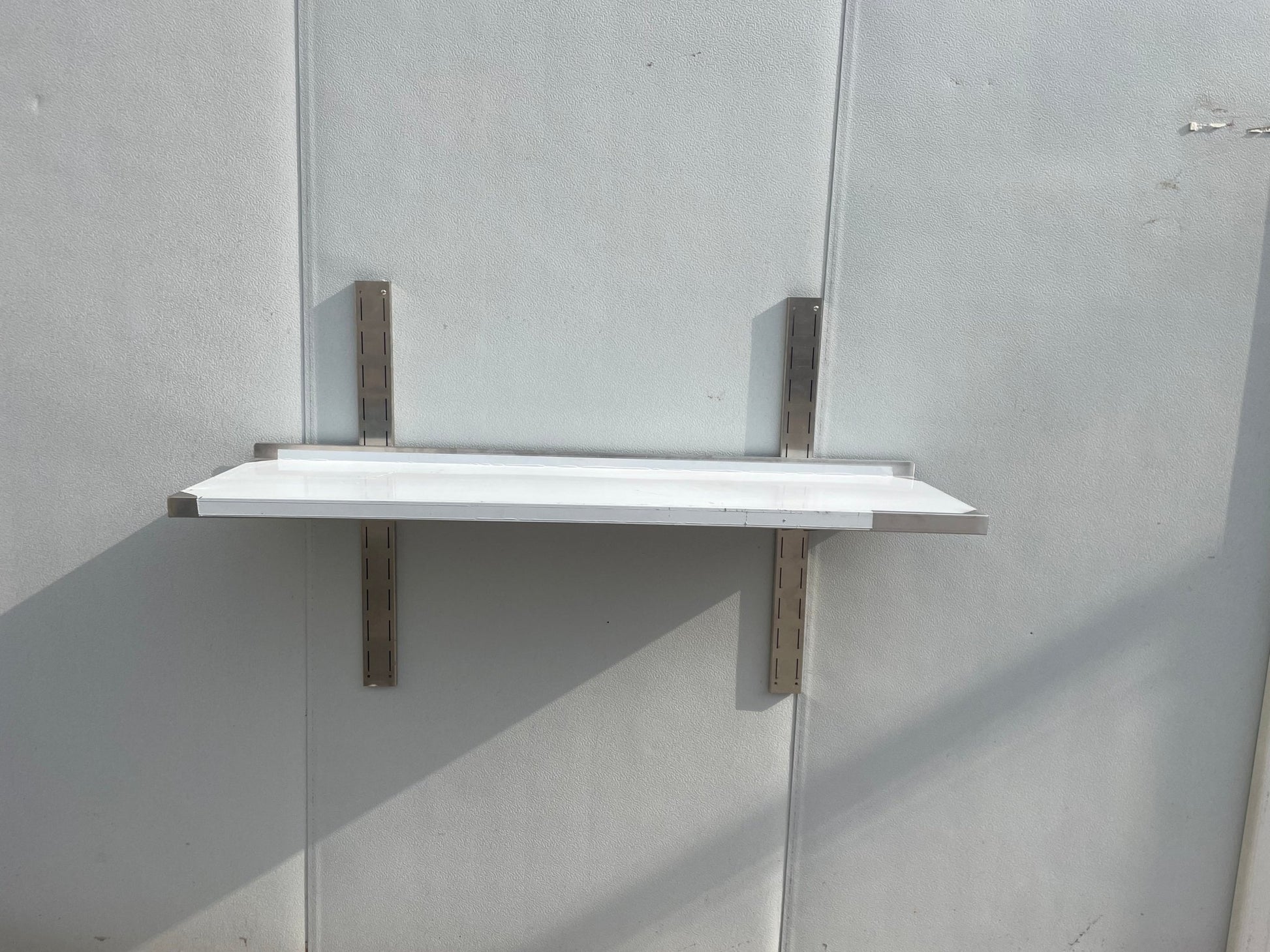 Stainless steel wall-mounted shelf front view

Close-up of shelf bracket and mounting

Side view of stainless steel shelf over prep station

Commercial wall shelf above kitchen counter

Single-tier wall shelf with polished finish