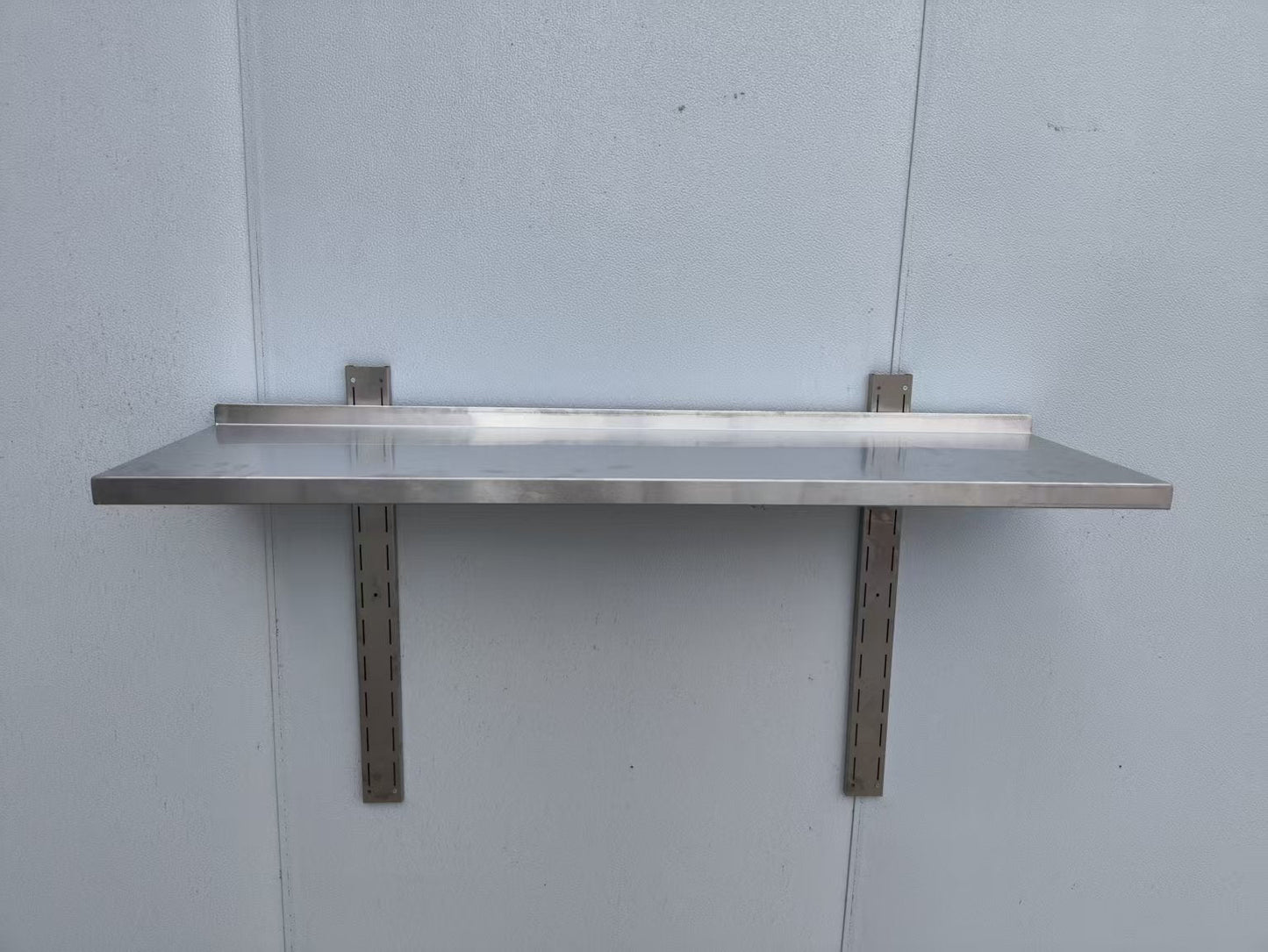 Stainless steel wall-mounted shelf front view

Close-up of shelf bracket and mounting

Side view of stainless steel shelf over prep station

Commercial wall shelf above kitchen counter

Single-tier wall shelf with polished finish