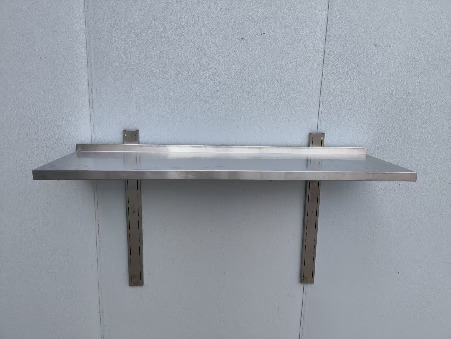 Stainless steel wall-mounted shelf front view

Close-up of shelf bracket and mounting

Side view of stainless steel shelf over prep station

Commercial wall shelf above kitchen counter

Single-tier wall shelf with polished finish