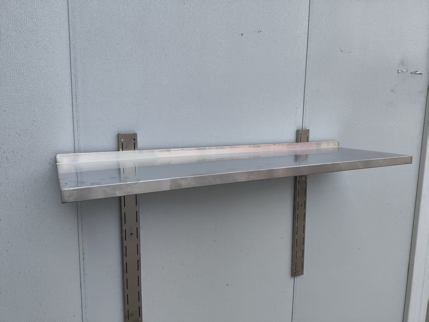 Stainless steel wall-mounted shelf front view

Close-up of shelf bracket and mounting

Side view of stainless steel shelf over prep station

Commercial wall shelf above kitchen counter

Single-tier wall shelf with polished finish