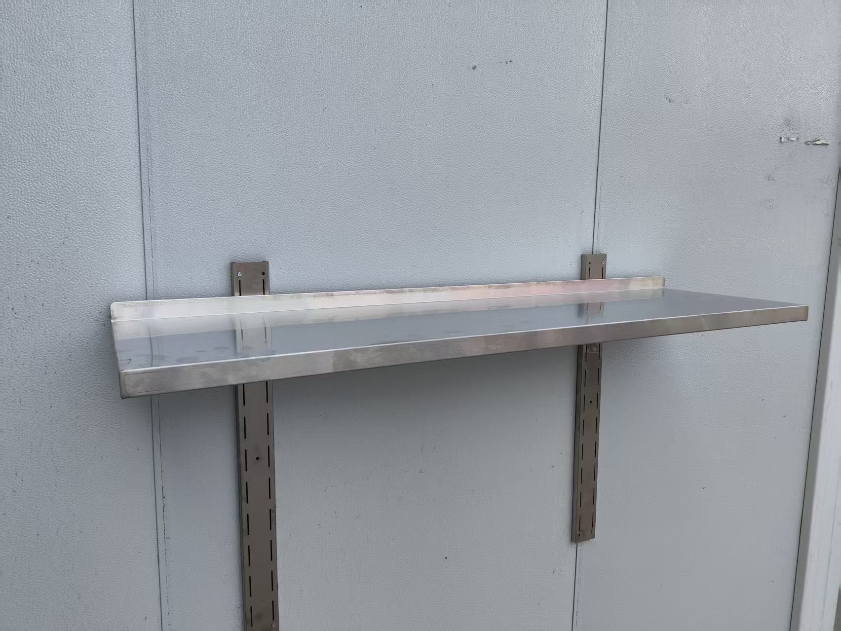 Stainless steel wall-mounted shelf front view

Close-up of shelf bracket and mounting

Side view of stainless steel shelf over prep station

Commercial wall shelf above kitchen counter

Single-tier wall shelf with polished finish