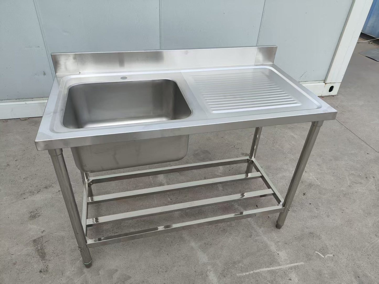 Stainless steel sink with right drainboard and backsplash

Freestanding commercial sink for food prep

Single bowl kitchen sink with undershelf

Heavy-duty stainless sink station front view

Restaurant-grade sink unit with drainboard