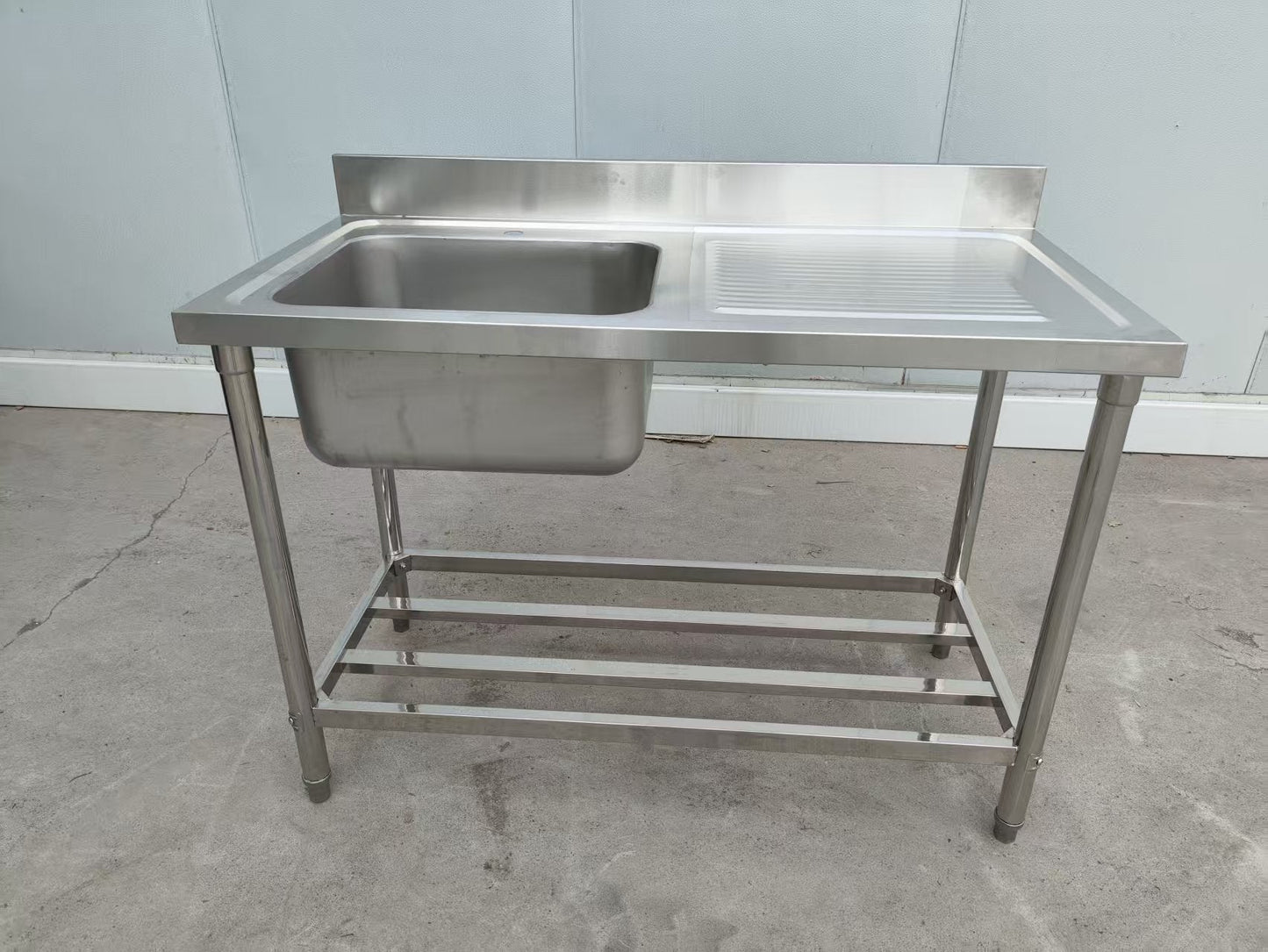 Stainless steel sink with right drainboard and backsplash

Freestanding commercial sink for food prep

Single bowl kitchen sink with undershelf

Heavy-duty stainless sink station front view

Restaurant-grade sink unit with drainboard