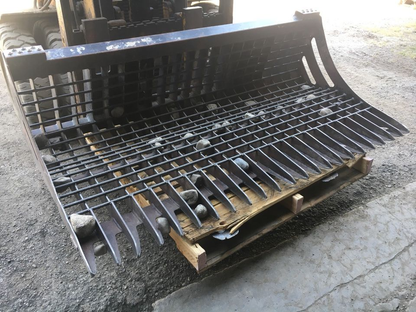 96" skid steer rock bucket with ½" spacing

Heavy-duty skeleton rock bucket on gravel

Close-up of angled bar structure

72" deluxe rock grapple for small rocks and debris

Skid steer lifting rock bucket attachment

